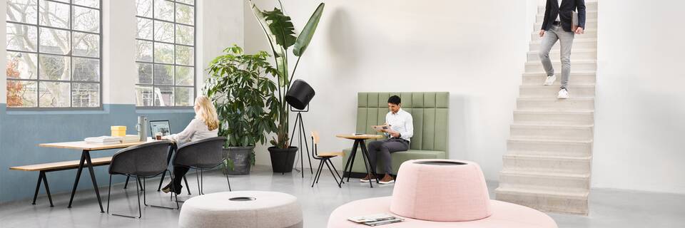 Pyramid, Well Armchair, Recharge 45, Recharge 100, Recharge 165, Result, Engage Ahrend Recharge poufs upholstered in pink yellow and grey with Pyramid and Well armchairs with models in a Hybrid working community setting