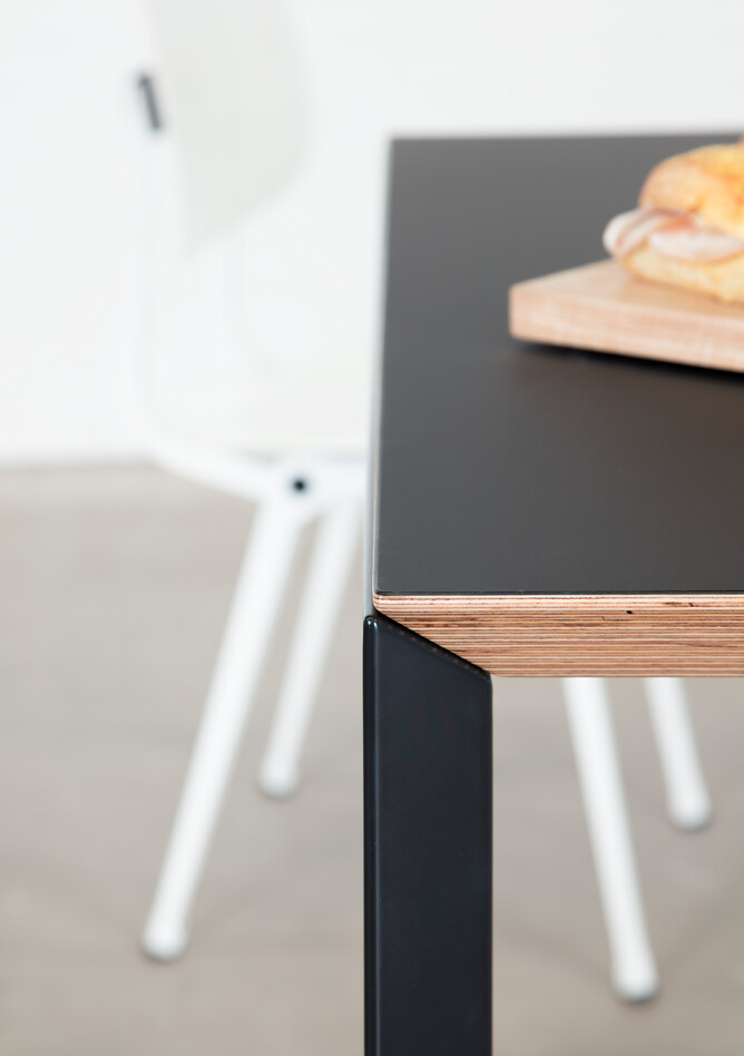 Delta, Revolt Royal Ahrend Delta table in black with black tabletop with white Revolt chair blurred and sandwich right side view
