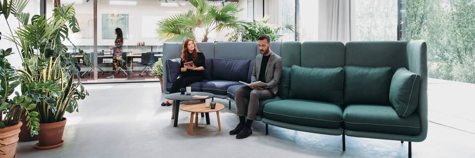 Embrace Royal Ahrend Embrace sofa upholstered in green and blue with female and male model at HofmanDujardin office in Diemen EB005