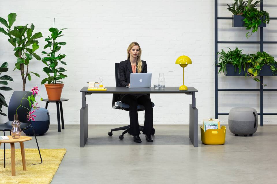 Balance Lift, Well, Recharge 45, 2020 Extra Verta Royal Ahrend Balance Lift workstation in grey with charcoal top and 2020 office chair with female model sitting front view