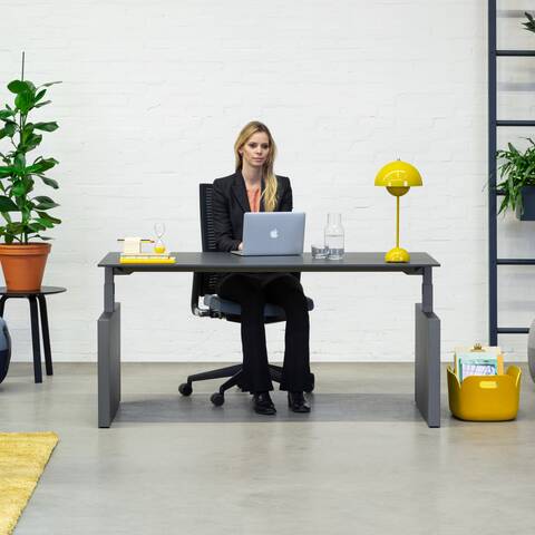 Balance Lift, Well, Recharge 45, 2020 Extra Verta Royal Ahrend Balance Lift workstation in grey with charcoal top and 2020 office chair with female model sitting front view