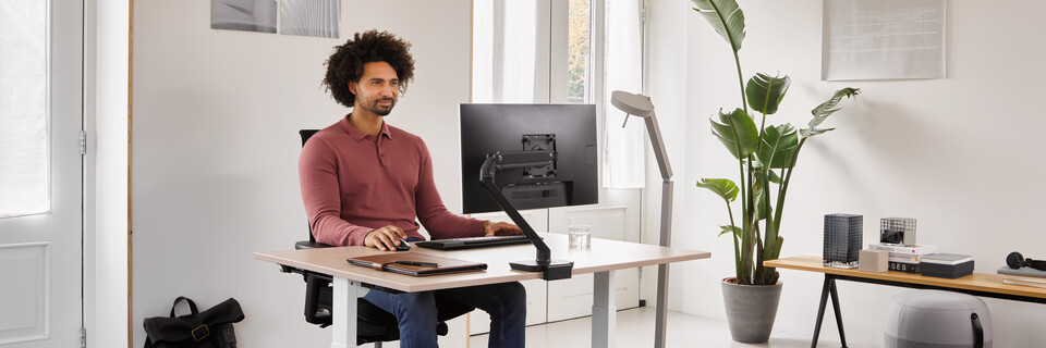 Home, Ease, Pyramid Bench 12, Recharge 45 Ahrend Home HVM desk in white with oak tabletop and black Ease office chair with grey Recharge and Pyramid bench with male model thinking in a work from home setting