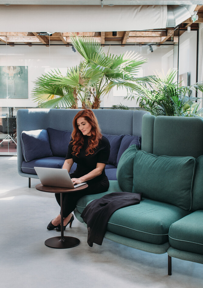 Embrace Royal Ahrend Embrace sofa upholstered in green and blue with female model at HofmanDujardin office in Diemen EB009