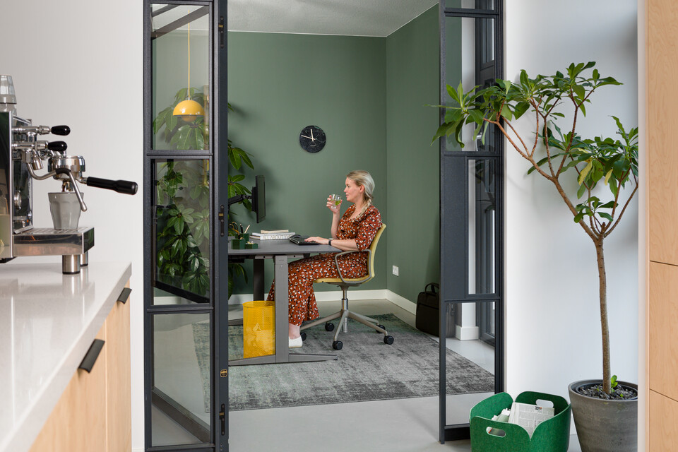 Balance Lift, Well Royal Ahrend balance workstation in grey with charcoal tabletop and Well chair upholstered in yellow and female model interior view
