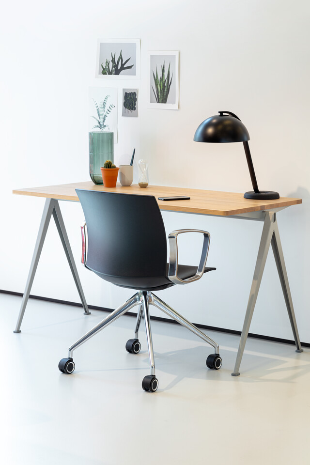 WELL Royal Ahrend Well trestle base chair on castors with polished chrome frame and armrests with anthracite shell and Pyramid table left rear view